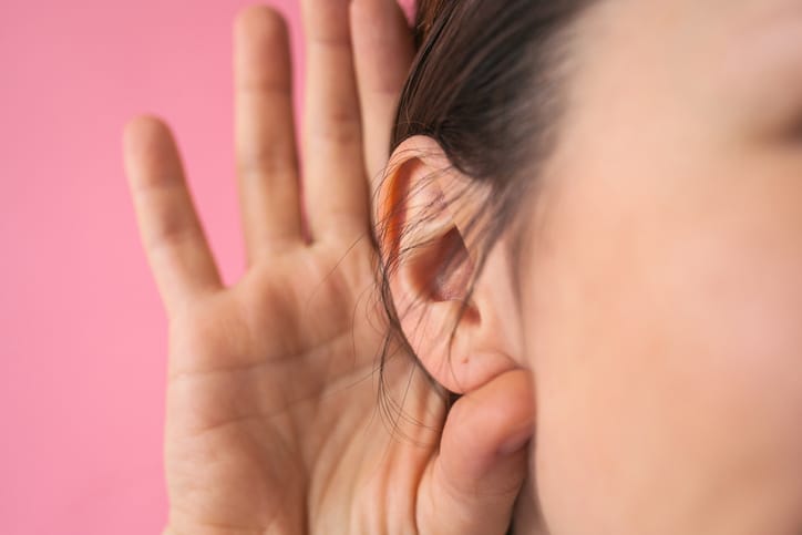 Close-up of a girl holding her hand next to her ear. The concept of chatter, gossip, news or secrets.