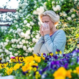 Woman covering sneeze in garden