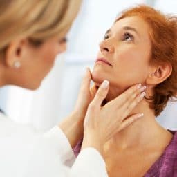 doctor feeling the outside of a woman's throat