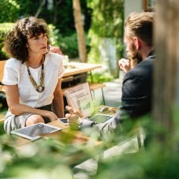 man and woman sitting at a table in a garden having a discussion
