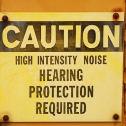 Metal caution sign for noise on industrial equipment