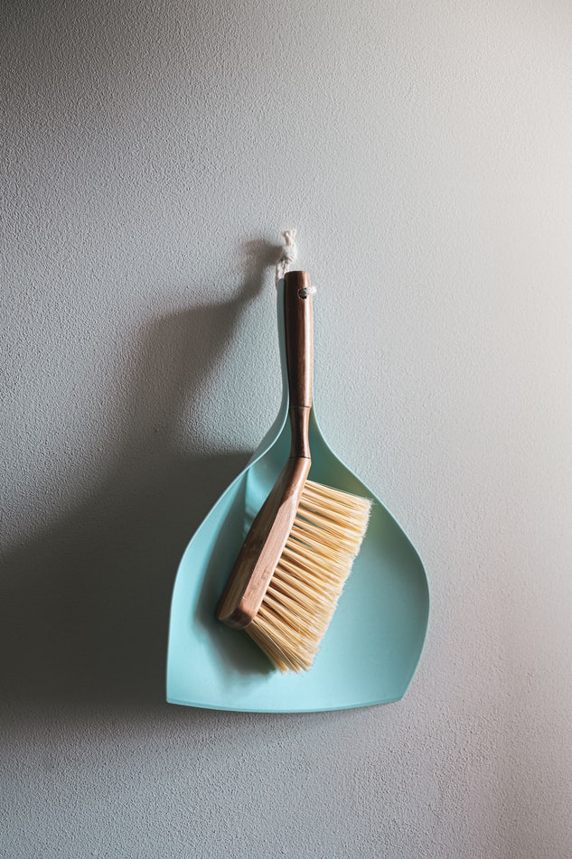 A dust pan with a brush hanging on a wall.