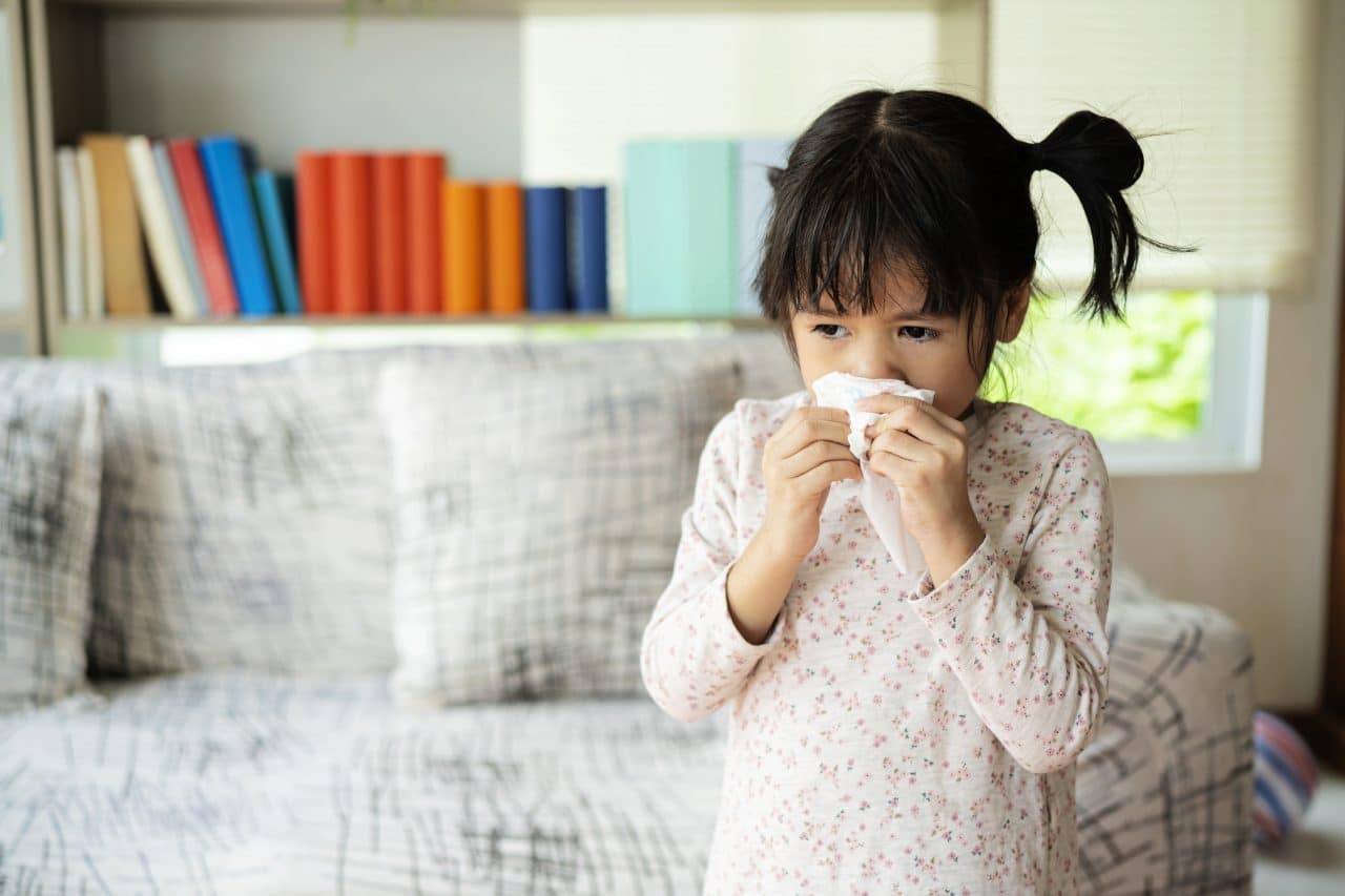 Little girl with allergies blowing her nose.