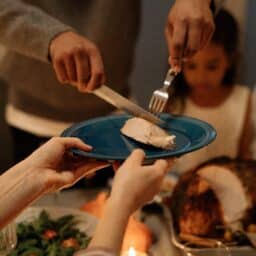 A family getting ready to eat thanksgiving together, cutting turkey on a plate.