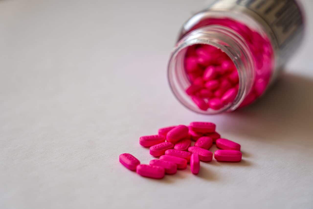 Pink capsules in a clear pill bottle.