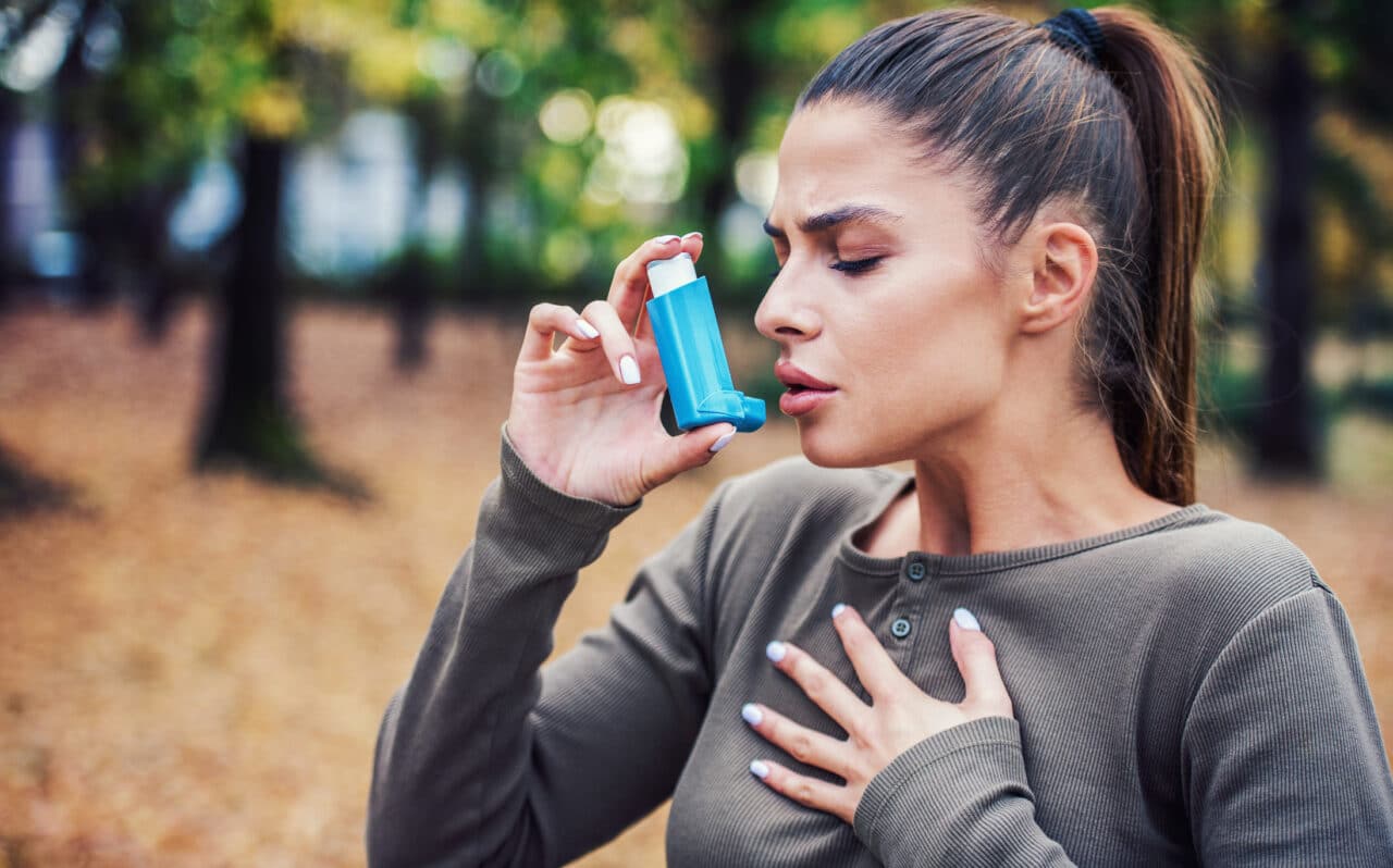 Young woman treating her asthma with an inhaler.