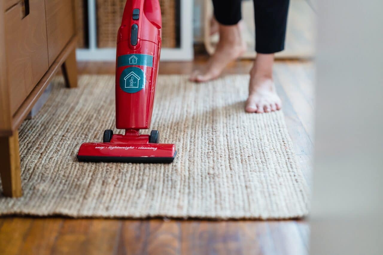 A person vacuuming a rug at home.