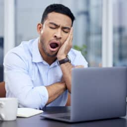 Young businessman yawning at his desk.