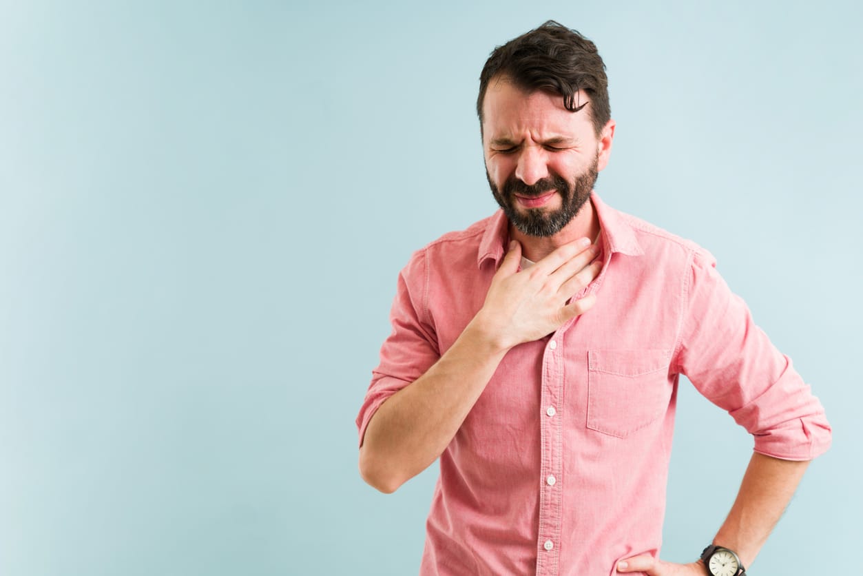 Man holding his chest experiencing heartburn