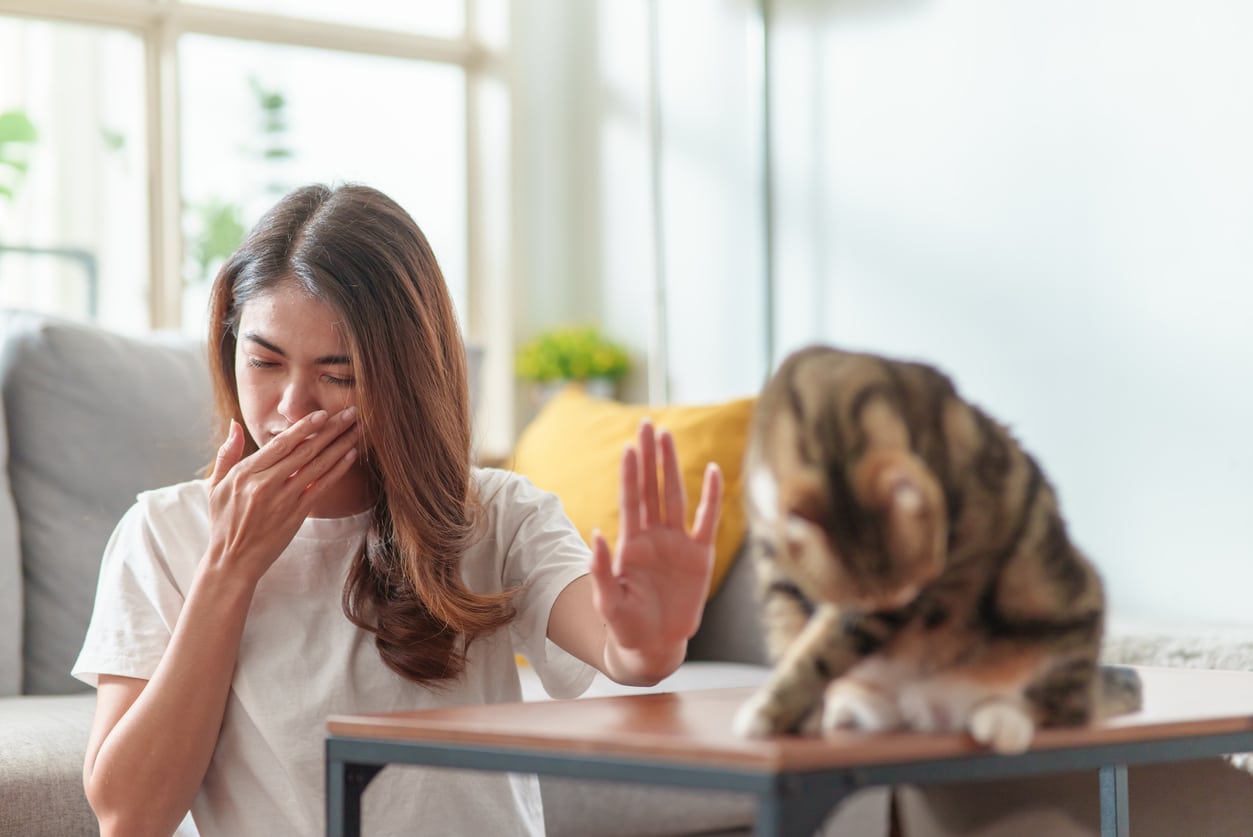 Woman with allergies putting a hand up to her cat.
