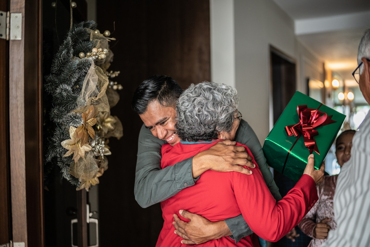 Two family member hugging, woman holding a gift box.