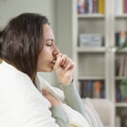 Coughing woman sitting on her couch