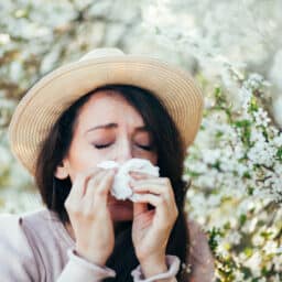 Woman sneezing around flowers