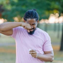 Man with allergies scratches eyes in park