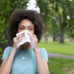 Woman with environmental allergies sneezing into a tissue