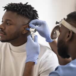 ENT specialist conducting an ear exam on a young man