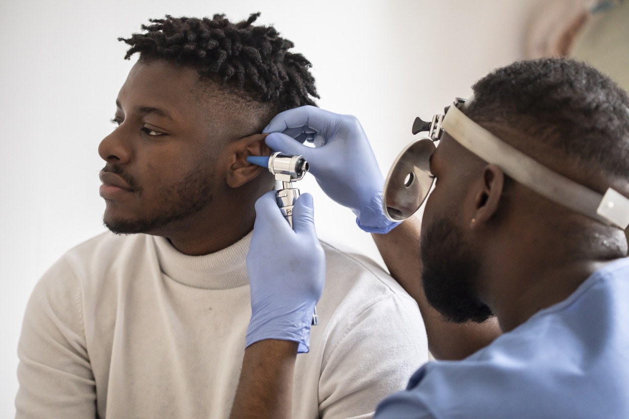 ENT specialist conducting an ear exam on a young man.