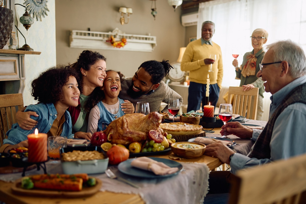 Happy family sitting down for Thanksgiving dinner.